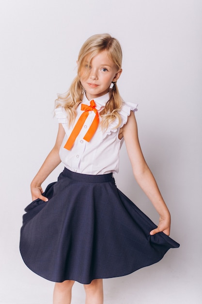 Leuk schattig Kaukasisch blondie meisje in schooluniform op witte achtergrond