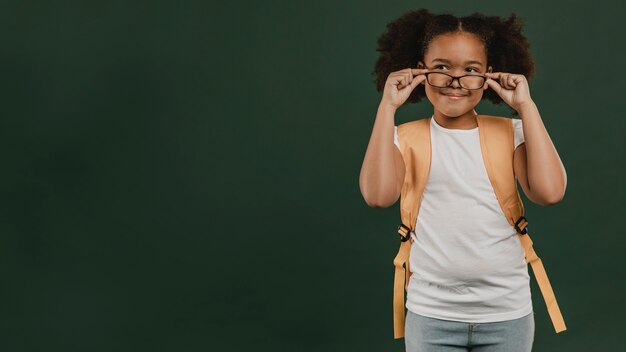 Foto leuk schoolmeisje dat haar leesbril schikt