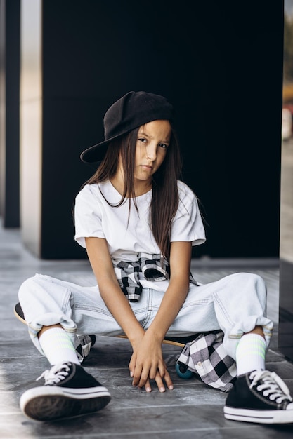 Leuk schoolmeisje met skateboard op straat