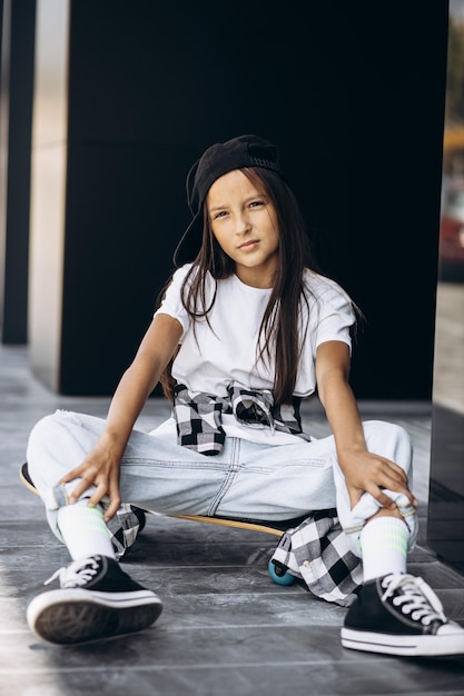 Leuk schoolmeisje met skateboard op straat