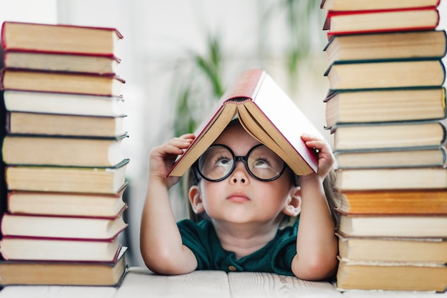 Leuk slim voorschools meisje dat boeken leest in de bibliotheek of thuis Kinderen leren al vroeg thuisonderwijs