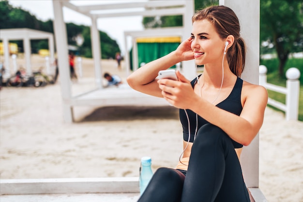 Leuk sportief meisje ontspannen buiten na de training met een fles water