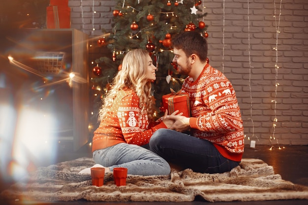 Leuk stel zit thuis bij de kerstboom.