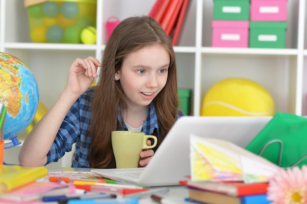 Leuk studentenmeisje bij klasse met laptop en thee