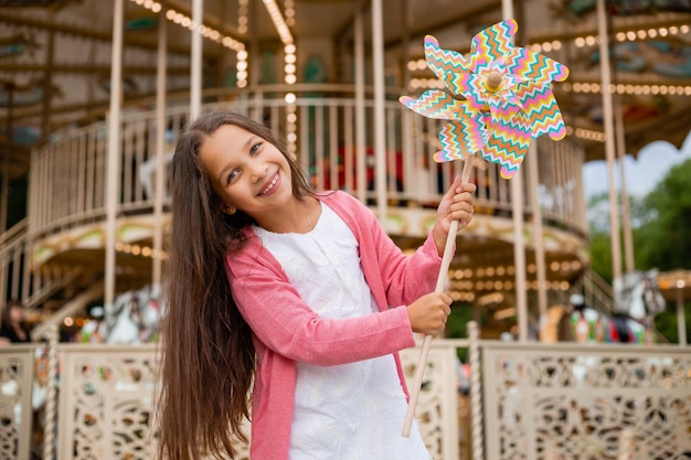 Leuk tienermeisje speelt dichtbij carrousel in stuk speelgoed briesje