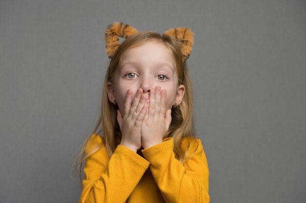 Leuk verrast blond meisje met tijgeroren een hoofdtooi met tijgeroren nieuwjaarskind in een tijgerkos...