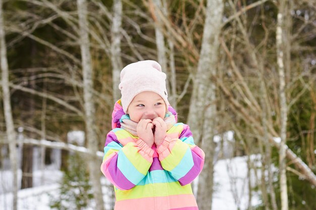 Leuk vrolijk peutermeisje in een besneeuwde bos heldere lentezonsneeuw