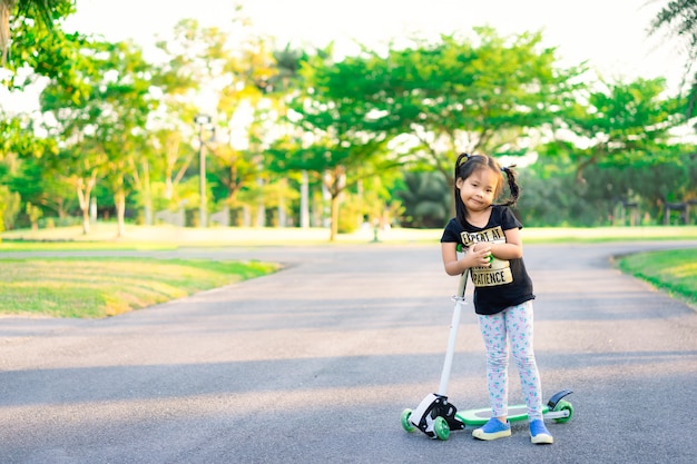 Leuk weinig Aziatisch meisje die een autoped in een park leren te berijden