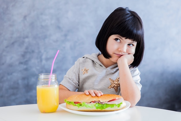 Leuk zwart haarmeisje die sandwich thuis eten