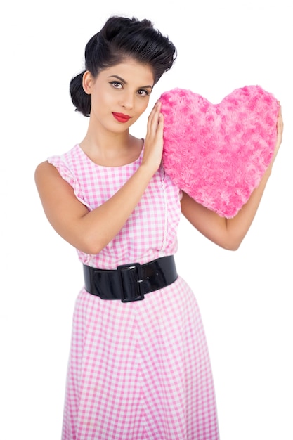 Leuk zwart haarmodel dat een roze hart gevormd hoofdkussen houdt