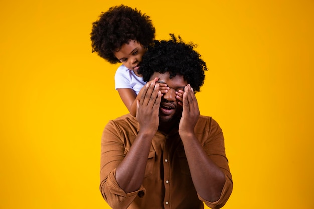 Leuke Afrikaanse peuterdochter die de ogen van haar vader sluit kind meisje dat verrassing maakt en een cadeau voorbereidt op vaderdag die plezier heeft met papa