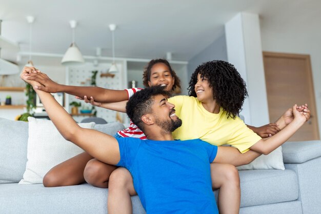 Leuke Afro-Amerikaanse familie geniet van tijd samen gelukkige ouders die glimlachen terwijl ze op de bank zitten met schattige dochter