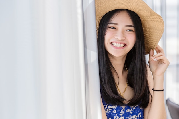 leuke Aziatische gril met de zomerkleding en hoed met het ontspannen stelt met witte ruimteachtergrond