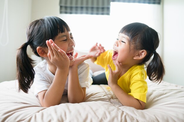 Leuke Aziatische kinderen die op het bed liggen