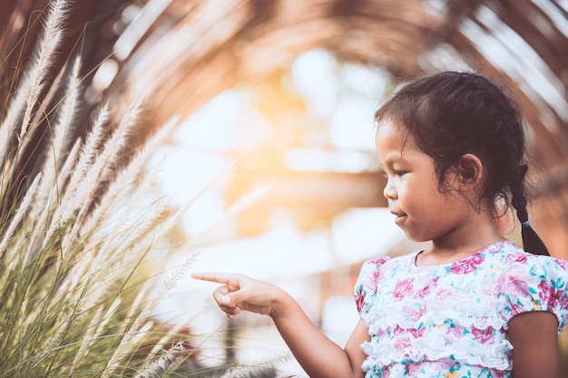 Leuke Aziatische klein kind meisje spelen met gras bloem in de tuin met geluk
