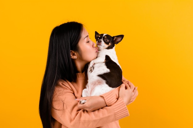 Leuke Aziatische vrouw met zijn chihuahua chihuahua hondenliefhebber Het geluk van een meisje dat van zijn hond houdt De liefde van mensen en schattige honden fotoshoot in oranje studio