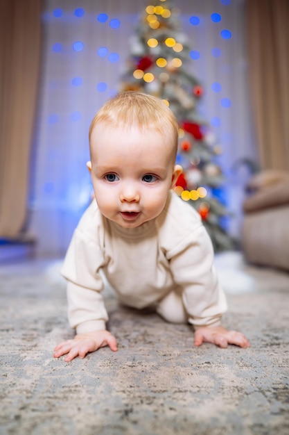 Leuke baby kruipt op de vloer voor de kerstboom.