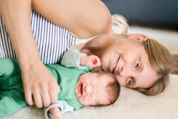 Foto leuke baby ligt op bed met moeder thuis.