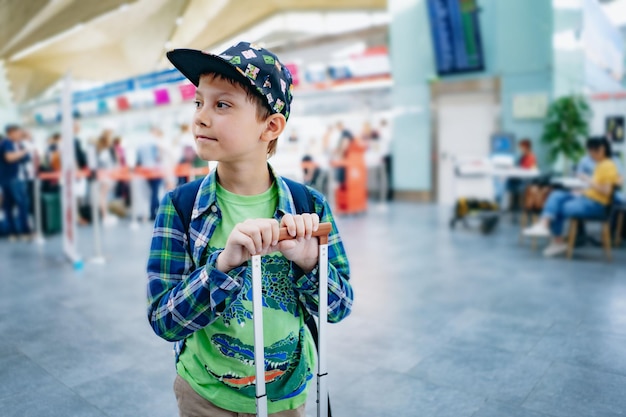 Leuke blanke jongen op de luchthaven met rugzak en koffer Reizend concept