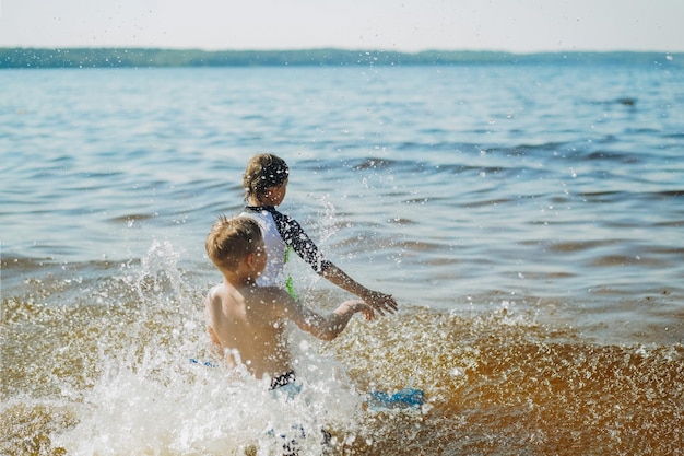 Leuke blanke jongens die in het water lopen met spatten en gelach Vacatiom aan zeezijde