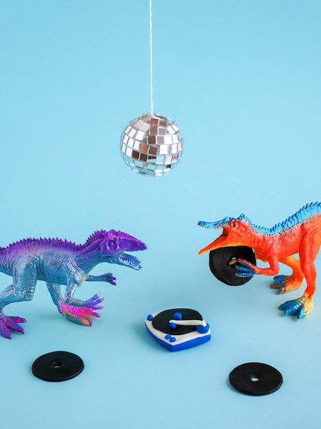 Foto leuke blauwe en oranje dinosaurus speelgoed luisteren vinyl op vinyl platenspeler met zijn vriend op blauwe achtergrond