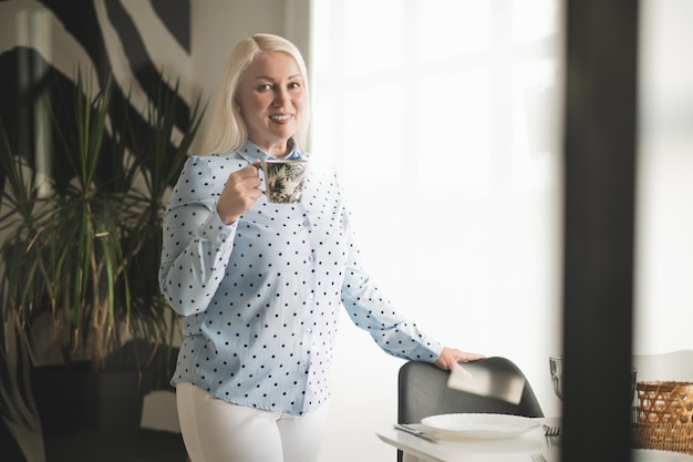 Leuke blonde vrouw met een koffiemok in handen