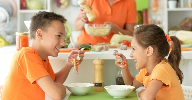 Leuke broer en zus die samen salade proeven in de keuken