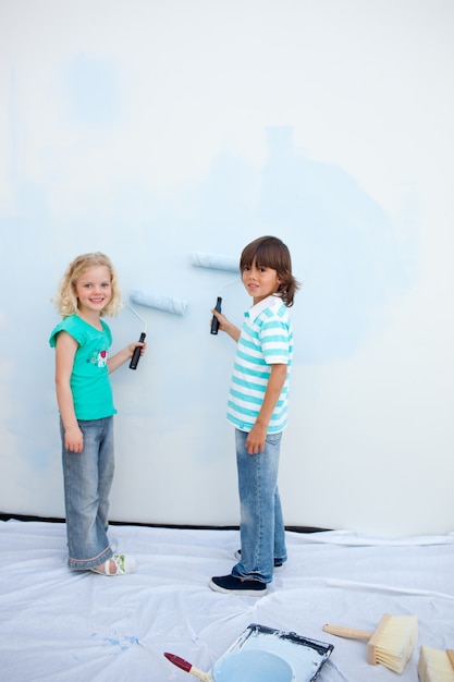 Leuke broers en zussen die een muur schilderen