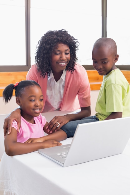 Leuke broers en zussen met behulp van laptop samen met moeder