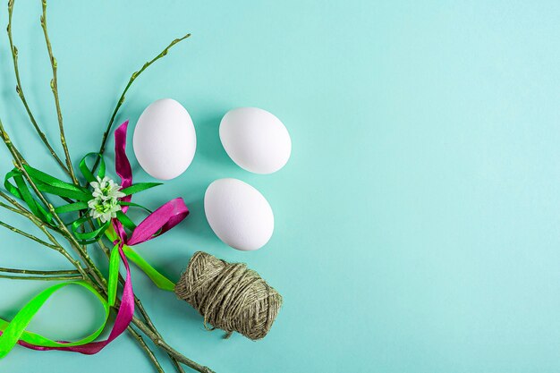 Leuke creatieve Pasen-samenstelling met witte eieren, wilgentwijgen en kleurrijke linten op groene achtergrond. DIY en kinderen creativiteit. Zelfgemaakt ambacht. Wenskaart, mock-up. Kopieer ruimte voor tekst
