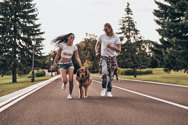 Leuke dag in het park. volledige lengte van een mooi jong stel dat met hun hond rent terwijl ze tijd buitenshuis doorbrengen