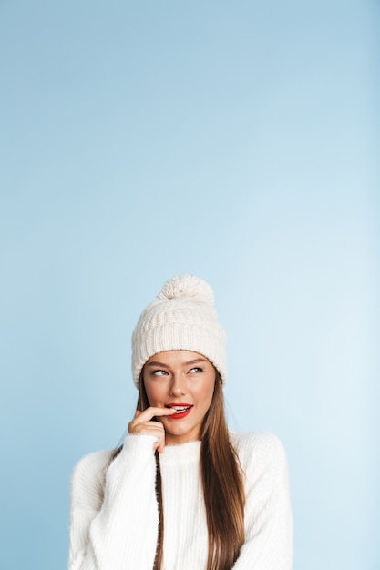 Leuke denkende jonge vrouw die de winterhoed draagt.