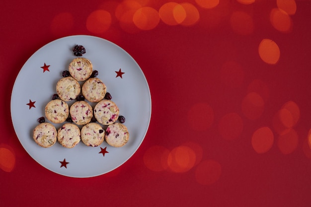 Leuke eetbare kerstboom gemaakt van koekjes op een ronde plaat op een rode achtergrond met bokeh