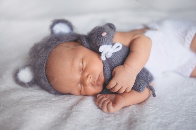 Leuke emotionele pasgeboren baby babyjongen slapen in wieg in een gebreid pak met speelgoed.