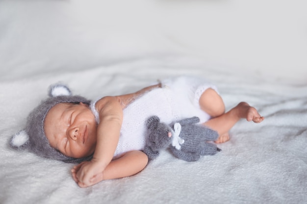 Leuke emotionele pasgeboren babyjongen slapen in wieg in een gebreid pak met speelgoed.