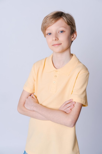 Leuke emotionele tienerjongen in geel t-shirt poseren in studio op licht