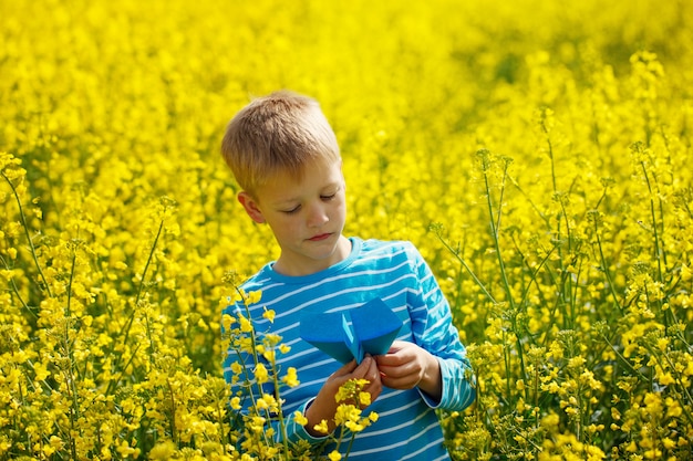 Leuke en gelukkige kleine jongen die met document vliegtuig in zonnige dag speelt