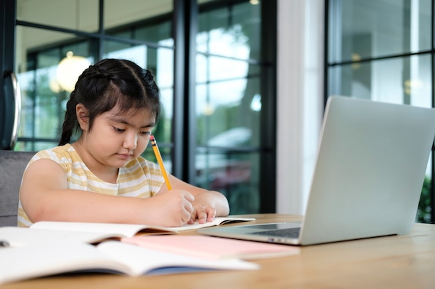 Leuke en gelukkige kleine meisjeskinderen die laptopcomputer gebruiken, die via online e-learningsysteem studeren.