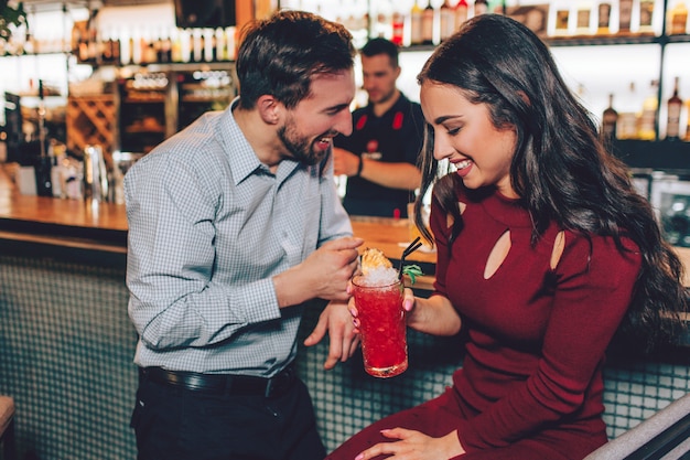 Leuke en jonge cCouple staan naast de stand van barman. Ze zien er verlegen maar gelukkig uit. Ook glimlachen en lachen ze.