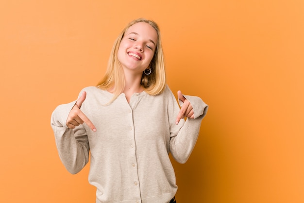 Leuke en natuurlijke tiener vrouw wijst naar beneden met vingers