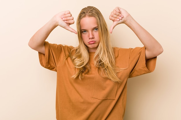 Leuke en natuurlijke tienervrouw die duim neer tonen en afkeer uitdrukken.