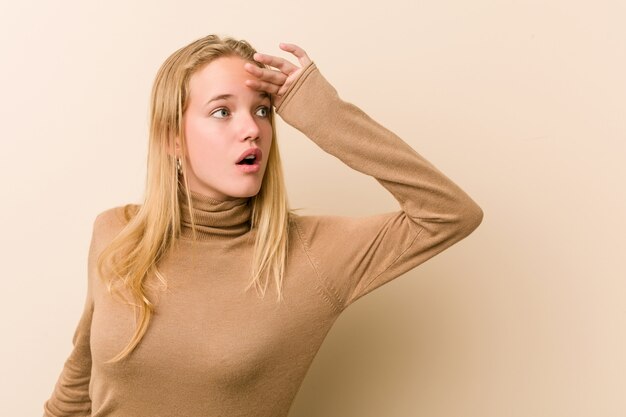 Foto leuke en natuurlijke tienervrouw die ver weg houdend hand op voorhoofd kijken.