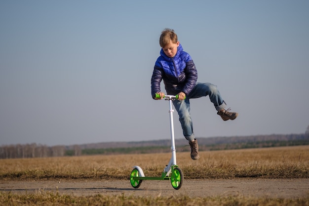 Foto leuke europese jongen rijden en trucs doen op scooter tijdens het lopen