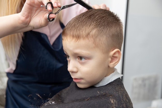 Leuke Europese kleine jongen die kapsel krijgt in de kapperszaak