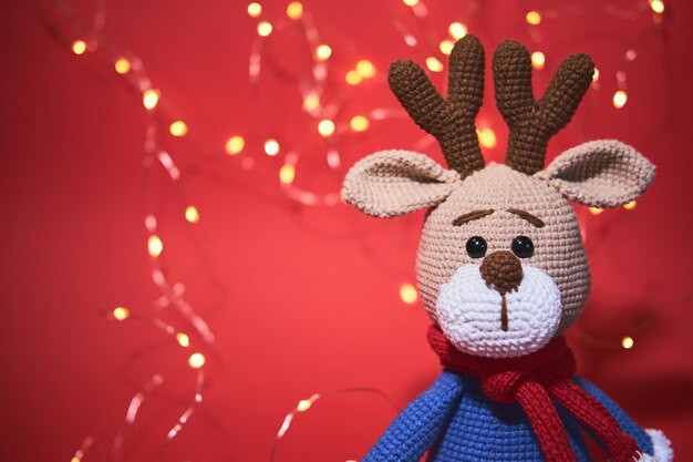 Leuke gebreide amigurumi herten op rode achtergrond met gele bokeh van slinger warme schaduw