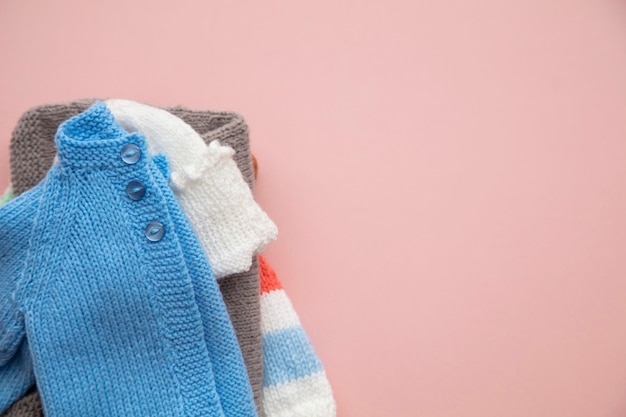 Leuke gebreide babykleding lay-out op een pastelroze achtergrond