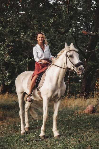 Leuke gelukkige jonge vrouw te paard in de zomer parklandschap