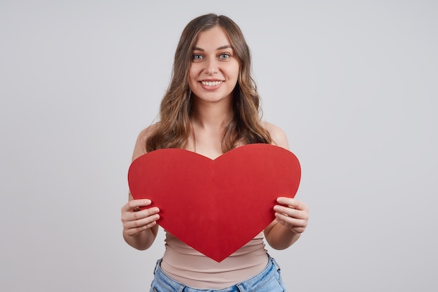 Leuke, gelukkige vrouw met een papieren hart, glimlachend.