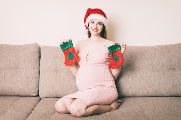 Leuke gelukkige zwangere vrouw in jurk thuis in KERSTMUTS Moeder om met grote buik te zijn overhandigt buik Merry Christmas holidays New Year Eve concept