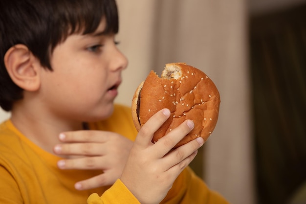 Leuke gezonde preschool jongen jongen eet hamburger zittend op school